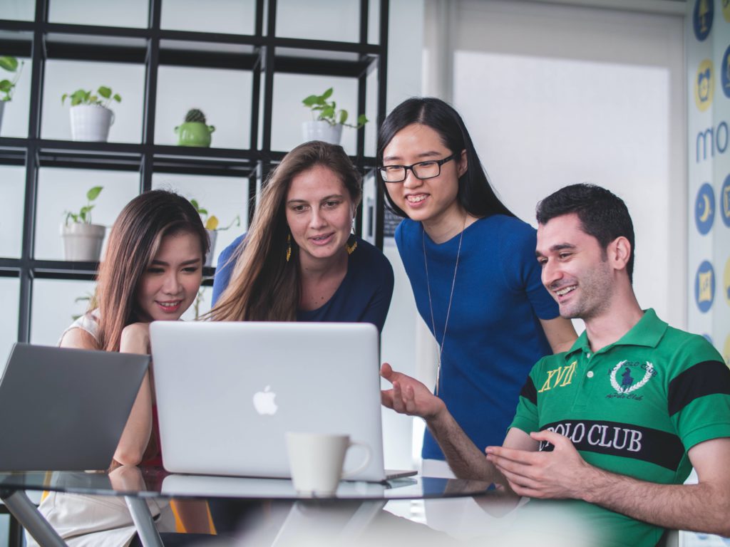Groupe de 4 personne souriant devant un ordinateur