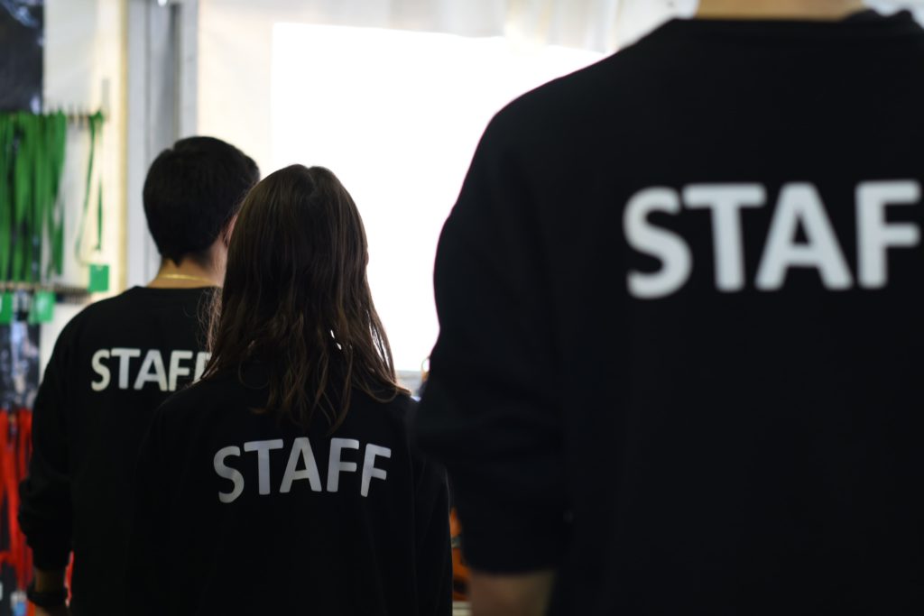 3 bénévoles dans un festival de musique de dos avec un tshirt "staff"