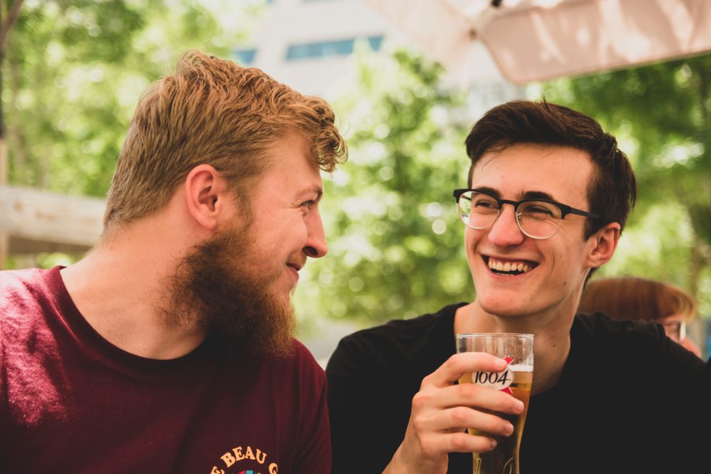 deux amis qui discutent autour d'une bières et sourient